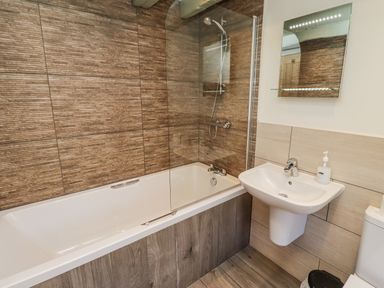 A bathroom with a bathtub, toilet, and sink at Millstone in Lucker