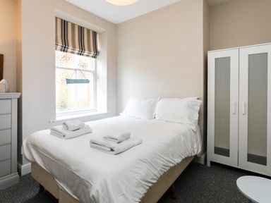 A bedroom with a bed towels wardrobe and a window with striped blinds at Baysyde in Alnmouth