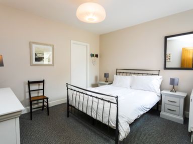 A bedroom with a double bed between two nightstands and a chair at Baysyde in Alnmouth