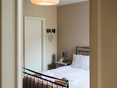 A bedroom with a bed a nightstand with a lamp and door at Baysyde in Alnmouth