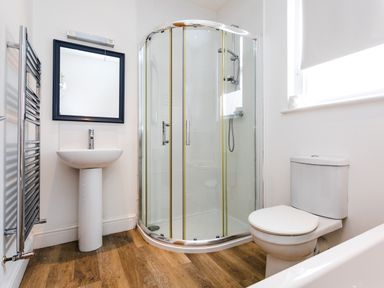 A bathroom with a shower enclosure sink mirror toilet and heated towel rail at Baysyde in Alnmouth