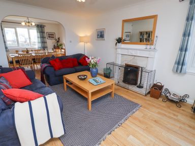 A living room with two sofas a coffee table and a fireplace opening to a dining room at Rathowen Beadnell