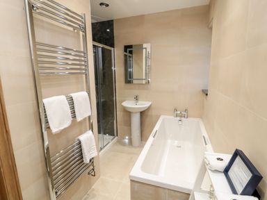 A bathroom with a bathtub sink shower area towel rack and mirror at Nook Cottage in Embleton