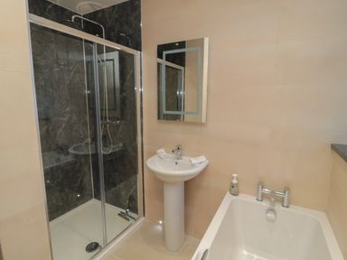 A bathroom with a shower enclosure a pedestal sink and a bathtub at Bothy Cottage in Embleton