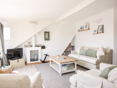 A living room with sofas coffee table television and bookshelf at The Penthouse @ No 5 in Lyme Regis