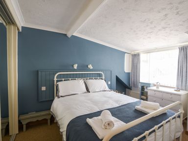 A bedroom with a white metal bed and blue accent wall at The Penthouse @ No 5 in Lyme Regis