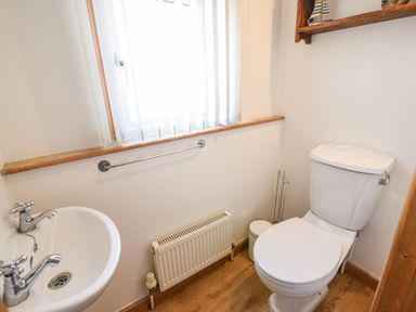 A small bathroom with a toilet a sink a window and a radiator at The Penthouse @ No 5 in Lyme Regis