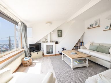 A living room with sofas a wooden coffee table a television and a window overlooking a parking lot at The Penthouse @ No 5 in Lyme Regis