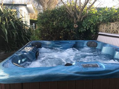 An outdoor hot tub with bubbling water surrounded by plants and a house at Pebble Reef in Easton Portland