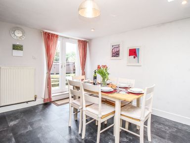 A dining room with a table set for six and a vase of flowers at Pebble Reef in Easton Portland