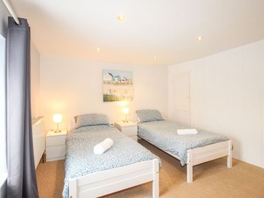 A bedroom with two single beds two nightstands with lamps and a painting on the wall at Pebble Reef in Easton Portland