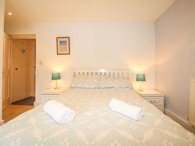 A bedroom with a double bed bedside tables with lamps and rolled towels at Pebble Reef in Easton Portland