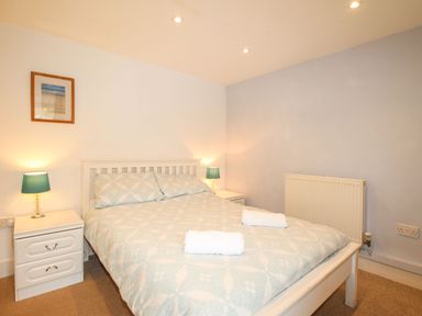 A bedroom with a double bed two bedside tables with lamps and a framed picture at Pebble Reef in Easton Portland