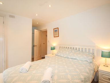 A bedroom with a bed with rolled towels and nightstands with lamps at Pebble Reef in Easton Portland