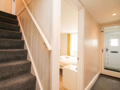 A hallway with carpeted stairs a white door with frosted glass and a bedroom with a bed and rolled towels at Pebble Reef in Easton Portland