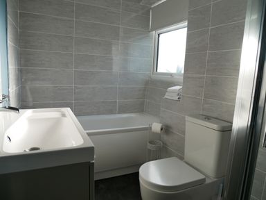 A bathroom with a sink, bathtub, toilet, and window at Pebble Reef in Easton Portland