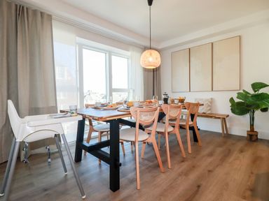 A dining room with a wooden table and chairs near large windows at 33 Cliff Edge in Newquay