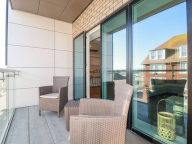 A balcony with two wicker chairs and a small table outside glass doors at 33 Cliff Edge in Newquay