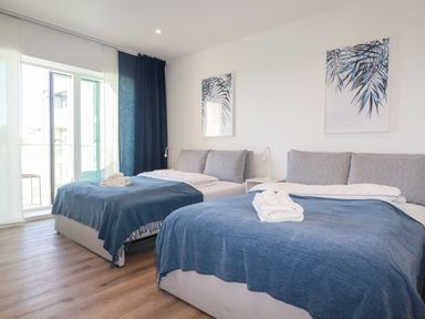 A bedroom with two beds covered with blue blankets and white towels on top at 33 Cliff Edge in Newquay