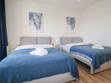 A bedroom with two beds covered with blue blankets and white towels on top at 33 Cliff Edge in Newquay