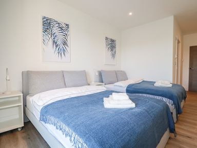 A bedroom with two beds covered with blue throws and white towels on top at 33 Cliff Edge in Newquay