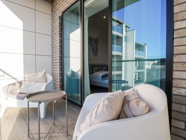 A balcony with two white armchairs and a small round table at 33 Cliff Edge in Newquay