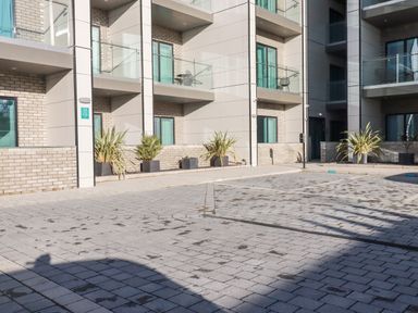 An exterior view of a modern apartment building with balconies potted plants and a paved courtyard at 33 Cliff Edge in Newquay