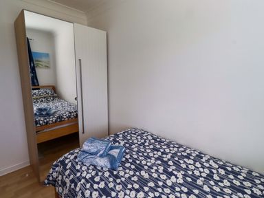 A bedroom with two beds and a wardrobe at 6 Westview Embleton