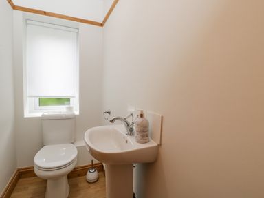 A small bathroom with a toilet and a pedestal sink with soap dispenser at 2 Church Street in Chipping Norton