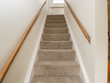 A carpeted staircase with wooden handrails on both sides at 2 Church Street in Chipping Norton