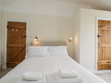 A bedroom with a bed with white linens and towels and wooden doors at 2 Church Street in Chipping Norton