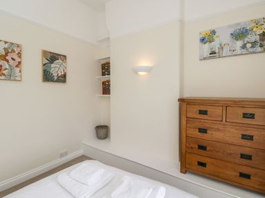 A bedroom corner with a wooden chest of drawers a bed with towels and framed botanical prints on the walls at 2 Church Street in Chipping Norton