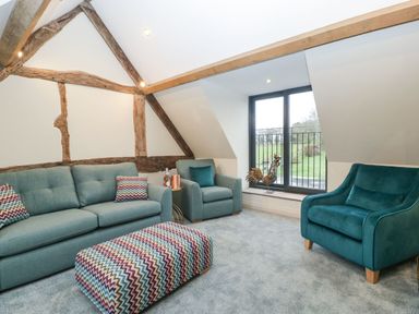 A sitting room with sofas cushions and a decorative rooster by the window at Palace Farmhouse in St Weonards