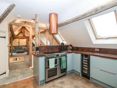 A kitchen with an oven and stove, wine cooler, skylights, and exposed wooden beams at Palace Farmhouse in St Weonards