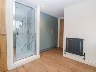 A room with a glass shower enclosure a gray radiator wooden doors and a large closet at Palace Farmhouse in St Weonards
