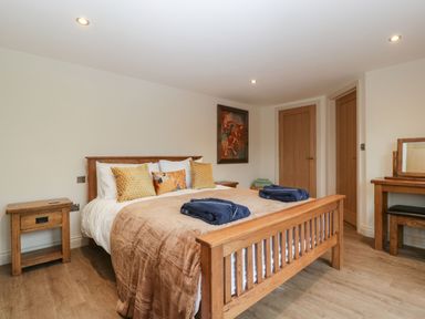 A bedroom with a wooden bed and bedside table with folded towels on the bed at Palace Farmhouse in St Weonards