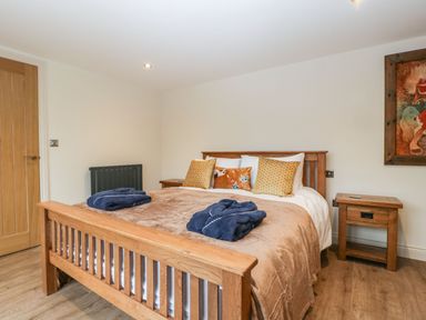 A bedroom with a wooden bed and matching bedside tables at Palace Farmhouse in St Weonards