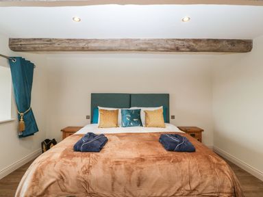 A bedroom with a double bed wooden bedside tables blue curtains and a wooden ceiling beam at Palace Farmhouse St Weonards