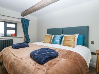 A bedroom with a double bed with pillows and robes near a window at Palace Farmhouse in St Weonards