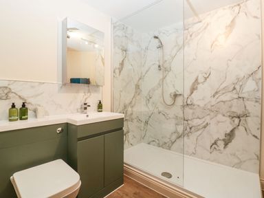 A bathroom with a toilet sink and shower with marble walls at Palace Farmhouse in St Weonards