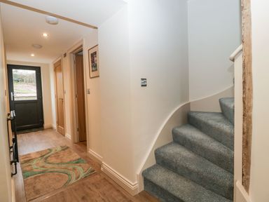 A hallway with wooden doors a patterned rug and carpeted stairs at Palace Farmhouse in St Weonards