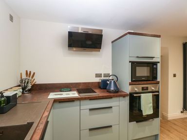 A kitchen with countertop appliances including a kettle and microwave ovens and a knife block at Palace Farmhouse in St Weonards
