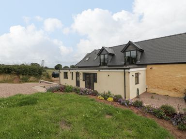 A house with a garden and flower bed in front of it at Palace Farmhouse in St Weonards