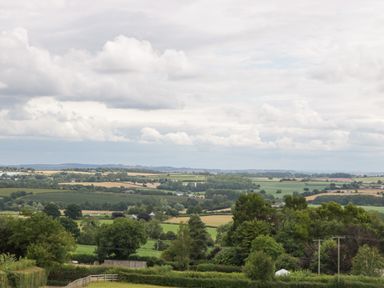 A rural landscape with fields trees and hedges under a cloudy sky at Palace Farmhouse in St Weonards
