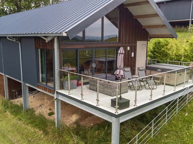 An outdoor area with decking, chairs and a hot tub at Bwncath in Garthmyl