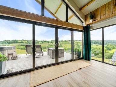 A living room with sliding glass doors leading to the deck at Bwncath in Garthmyl