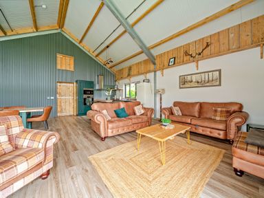 A living room with furniture and kitchen area at Bwncath Garthmyl