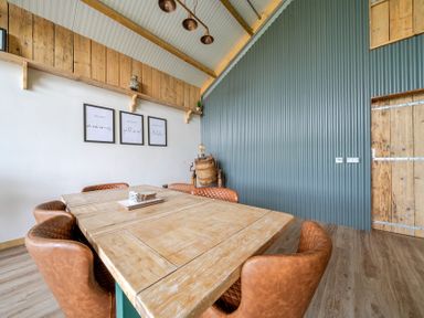 A dining room with a wooden table and leather chairs at Bwncath in Garthmyl