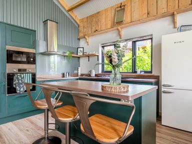 A kitchen with a refrigerator and bar stools at Bwncath in Garthmyl