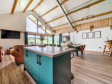 A living room featuring a sofa and dining table at Bwncath in Garthmyl